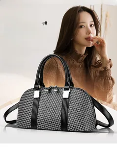 Detail of grey plaid woven texture and black leather handles on a structured handbag