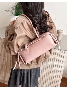 Detail of dusty pink cylinder shoulder bag with silver eyelets and leather tassels