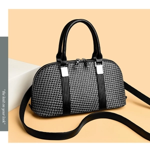 Close-up of knit Boston bag texture with black leather handles and silver hardware detail