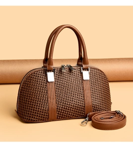 Detail of brown woven texture handbag with leather handles and detachable strap