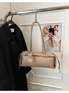 Detail of khaki leather shoulder bag with metallic buckle strap hanging on a hanger