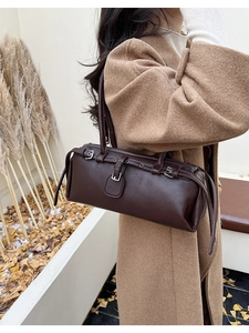 Detail of dark brown litchi pattern leather baguette bag with silver buckles on shoulder