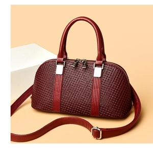Detail of burgundy shell-shaped handbag with woven texture and silver hardware accents