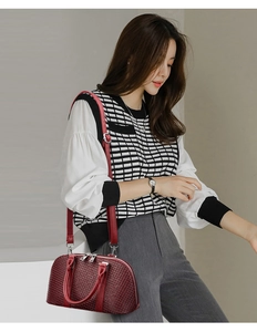 Close-up of a burgundy woven texture handbag with dual handles and a metallic zipper