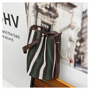Detail of striped woven bucket bag featuring green and white mesh with brown leather trim