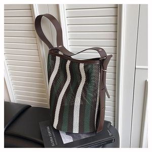 Close-up of woven mesh texture and premium brown leather trim on the striped tote bag