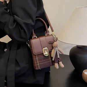 Detail of vintage plaid handbag with brown leather flap and cute plush bunny charm