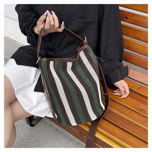 Detailed texture of green and white woven bucket bag with brown leather strap