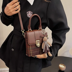 Close-up of brown plaid box bag with cute rabbit pendant and golden clasp