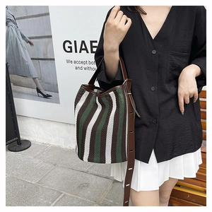 Detail of adjustable leather strap and mesh stripe texture on striped bucket bag