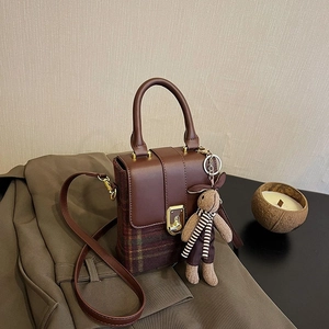 Detail of vintage plaid crossbody bag with metal handle and cute rabbit charm accent