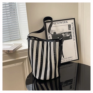 Detail of minimalist black and white striped mesh tote bag with black leather handle