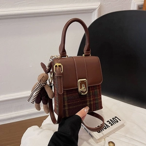 Detail of vintage plaid box bag with gold buckle and a cute rabbit doll charm