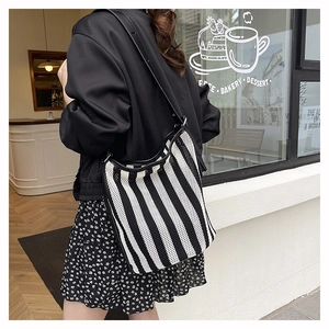 Detail of knit striped tote bag with leather strap shown in a lifestyle street view