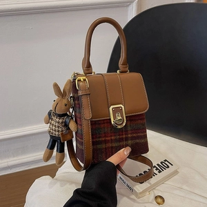 Detail of vintage checkered bag with brown leather trim and cute rabbit doll charm