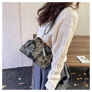 Gros plan d'un sac vintage brodé avec motifs floraux dorés et chaîne de perles