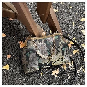 Détail d'un sac en brocart noir vintage avec broderie dorée et fermoir perle