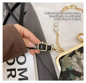 Détail de la bandoulière réglable en cuir noir d'un sac de soirée à fleurs brodées