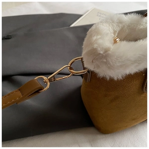 Detail of plush bucket bag showing suede texture and gold metal carabiner hook