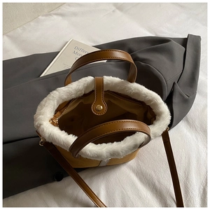 Detail view of brown leather bucket bag with white faux fur trim and adjustable strap