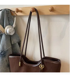 Detail of vintage brown suede tote bag featuring durable handles and metal connectors