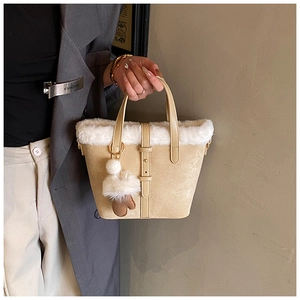 Close-up of khaki bucket bag with white plush faux fur trim and decorative buckle strap