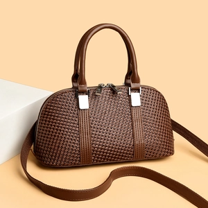 Deep brown woven shell handbag with double zippers and adjustable strap in minimalist studio