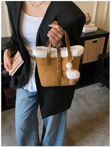 Brown suede handbag with white faux fur trim and fluffy pom-pom detail in winter style