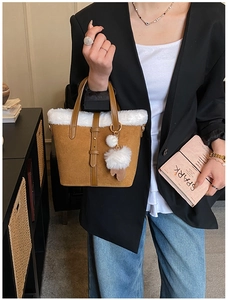 Detail of brown suede handbag with white faux fur trim and elegant slim handles