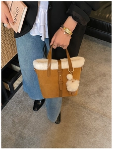 Close-up of brown suede tote bag with white faux fur trim and fluffy ball charm