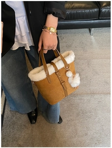 Close-up of brown suede handbag with white faux fur trim and pom-pom detail for winter