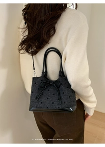 Détail d'un sac seau rétro en laine grise à pois noirs avec un nœud élégant en cuir