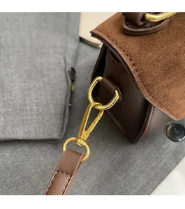 Dettaglio della fibbia dorata e della texture in pelle scamosciata della borsa