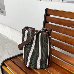 Striped mesh tote bag in forest green and cream white on a dark wooden bench