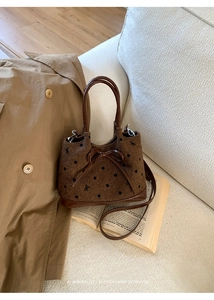 Sac à main marron à pois avec nœud sur un canapé blanc avec livres et trench-coat