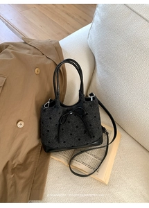 Détail d'un sac à main gris foncé à pois avec nœud décoratif et bandoulière longue
