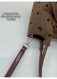 Close-up of detachable leather strap with silver lobster clasp on polka dot bucket bag