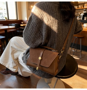 Dettaglio della borsa a tracolla marrone vintage con texture opaca e fibbia in metallo