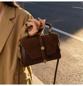 Dettaglio della borsa vintage marrone scuro con trama opaca e fibbia dorata alla luce del sole