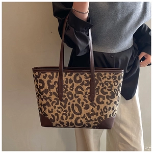 Detail of leopard print tote bag with brown leather reinforcement and woven canvas texture