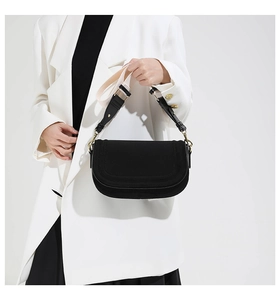 Detail of black suede saddle bag with vintage gold buckle and dual leather fabric straps