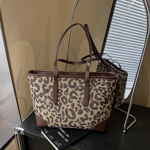 Detail of leopard print tote bag with brown leather handles and reinforced base corners