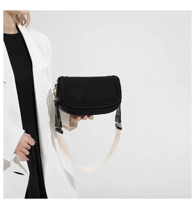 Detail of black flap shoulder bag with gold hardware and contrast wide strap