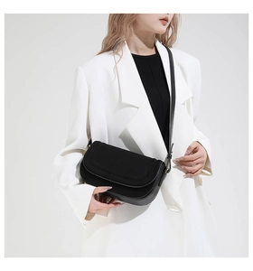 Minimalist black leather and suede flap bag shown on a model with white blazer