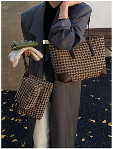 Detail of houndstooth tote bag set with brown leather accents in autumn scenery