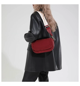 Detail of red leather saddle bag with wide woven strap on a black leather jacket