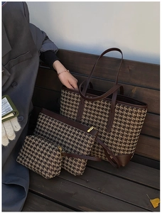 Detailed view of coffee houndstooth woven tote bag set with brown leather trim on a bench
