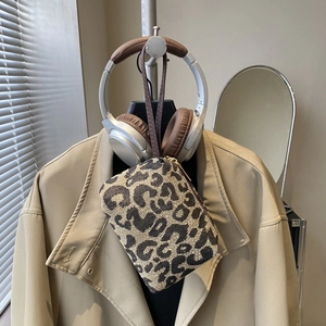 Detail of leopard print jacquard knitting texture and brown leather strap on pouch