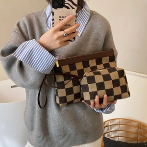Detail view of the brown checkerboard patterned pouch set with elegant gold hardware