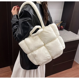 Detail of white quilted puffer tote bag with thick padded shoulder straps on model